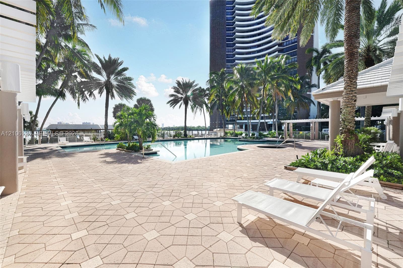 Swimming pool with tile surround, integrated spa, pergola-covered terrace, and landscaped perimeter