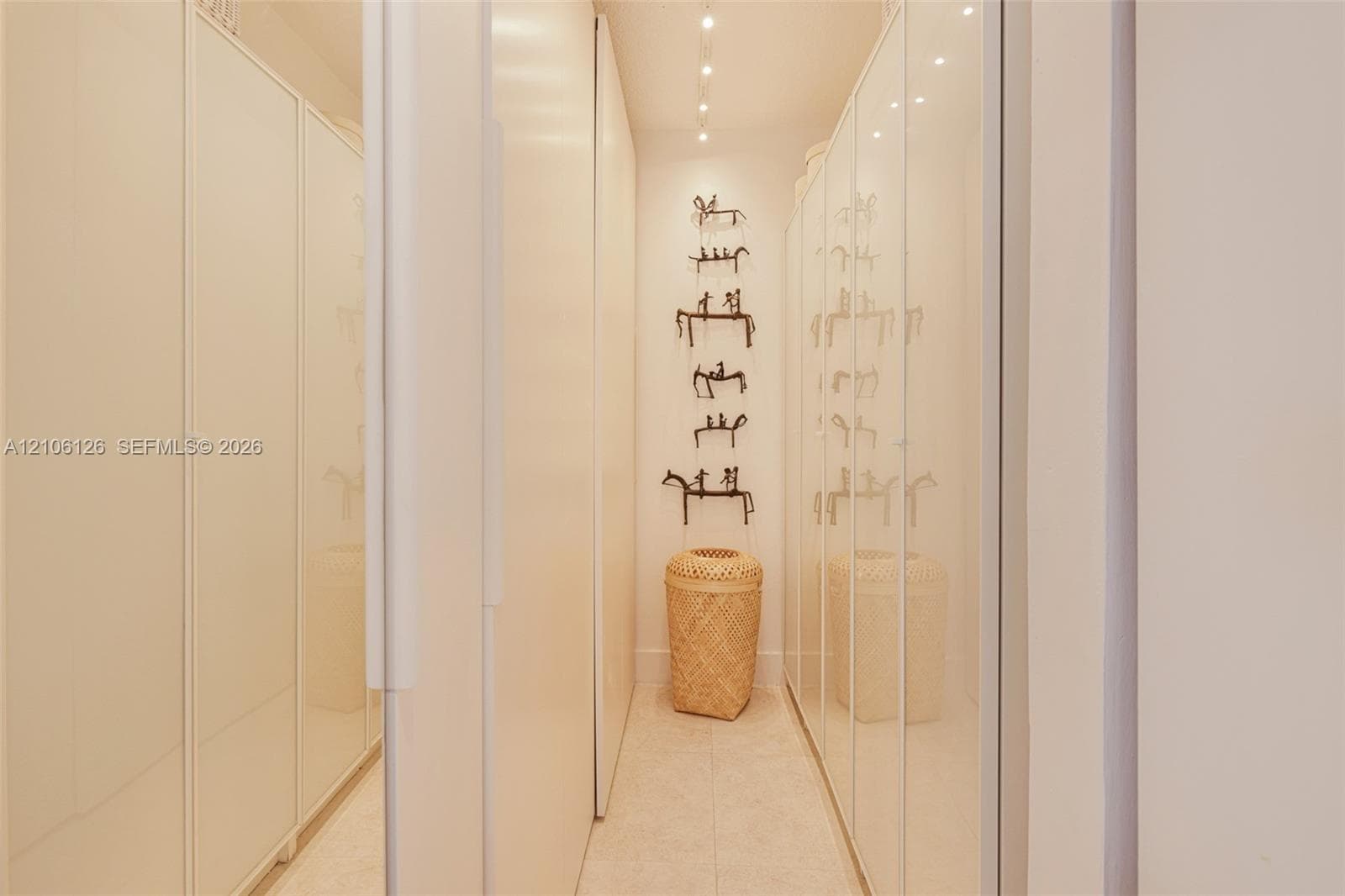 Modern bathroom featuring a wall-mounted floating vanity with a stone countertop, dual chrome faucets, a glass-enclosed walk-in shower with stone tile wall surfacing, and floor-to-ceiling built-in cabinetry