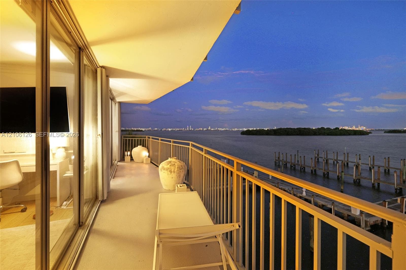 Private balcony featuring a metal railing, floor-to-ceiling glass sliding doors, and waterfront scenery
