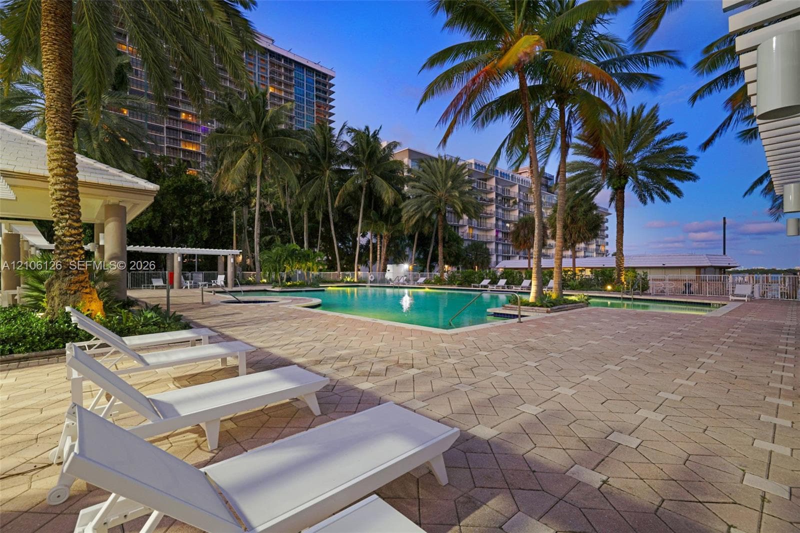 Swimming pool with integrated spa, concrete paver patio, and mature palm trees