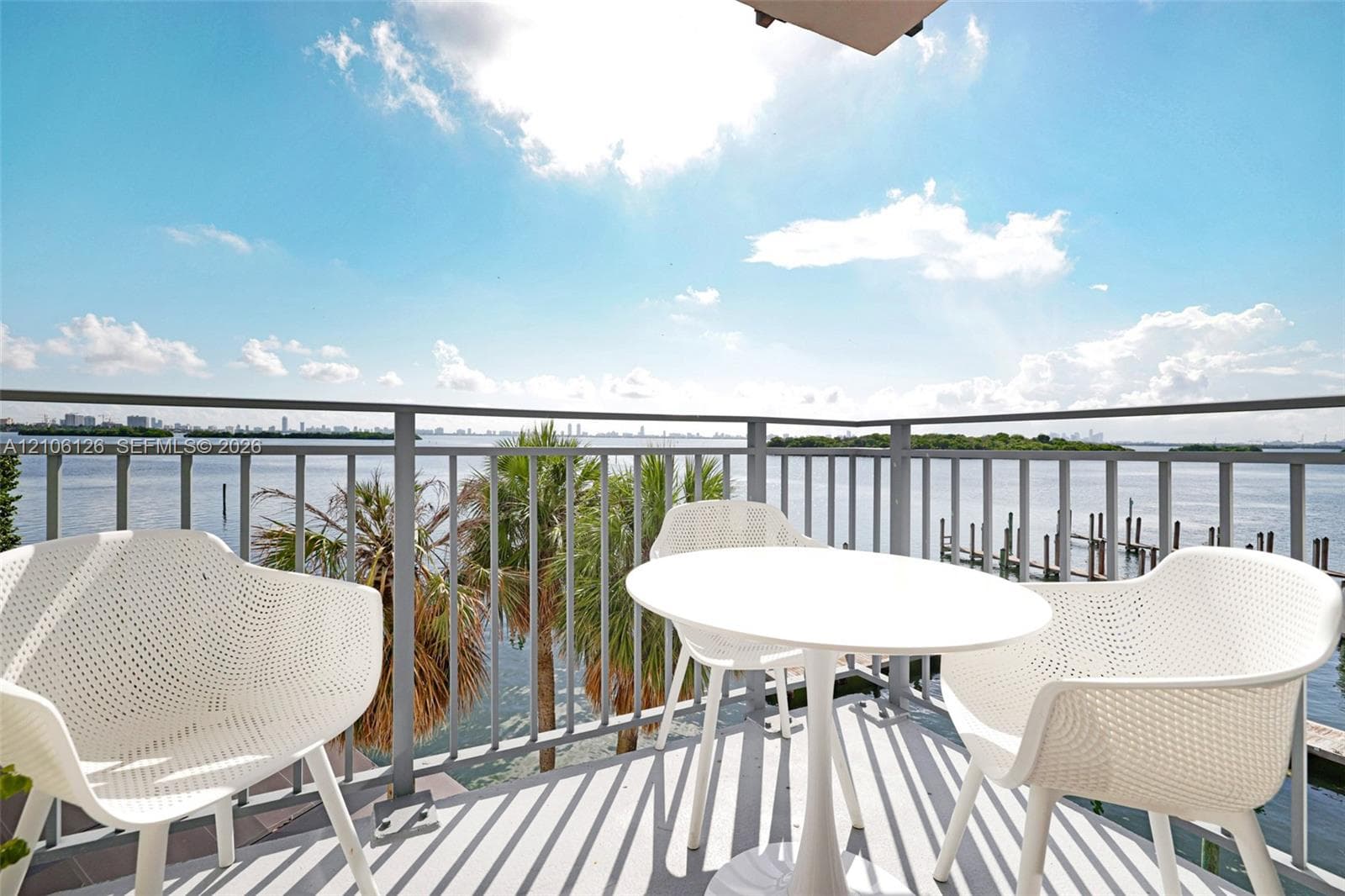 Covered balcony featuring a metal railing and expansive water frontage with a private dock system