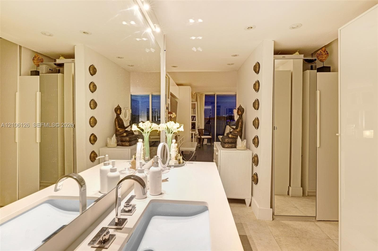 Floor-to-ceiling glass sliding doors, private balcony with metal railing, and water scenery