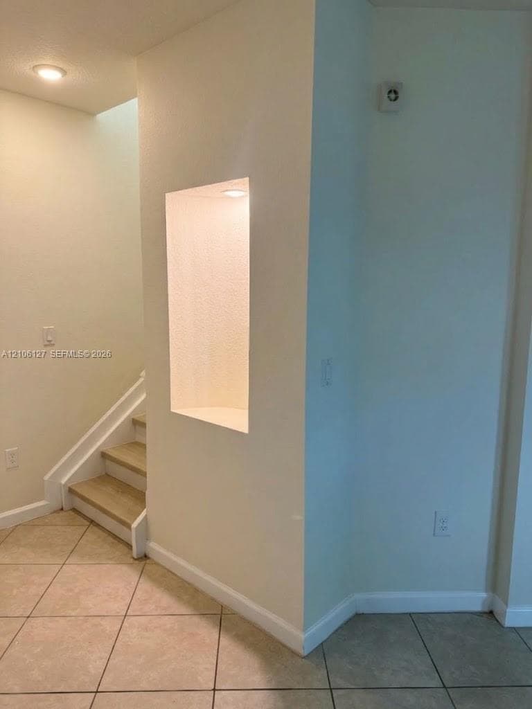 Recessed wall niche with integrated lighting, wood-finish stair treads, and tile flooring