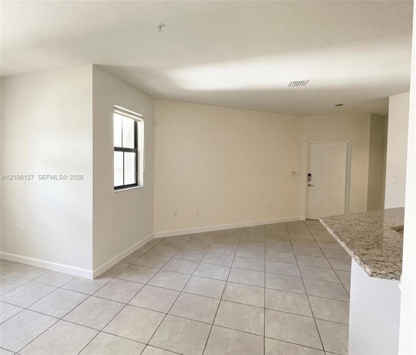 Neutral-toned tile flooring, solid-surface countertop with speckled finish, and multi-pane window with dark framing
