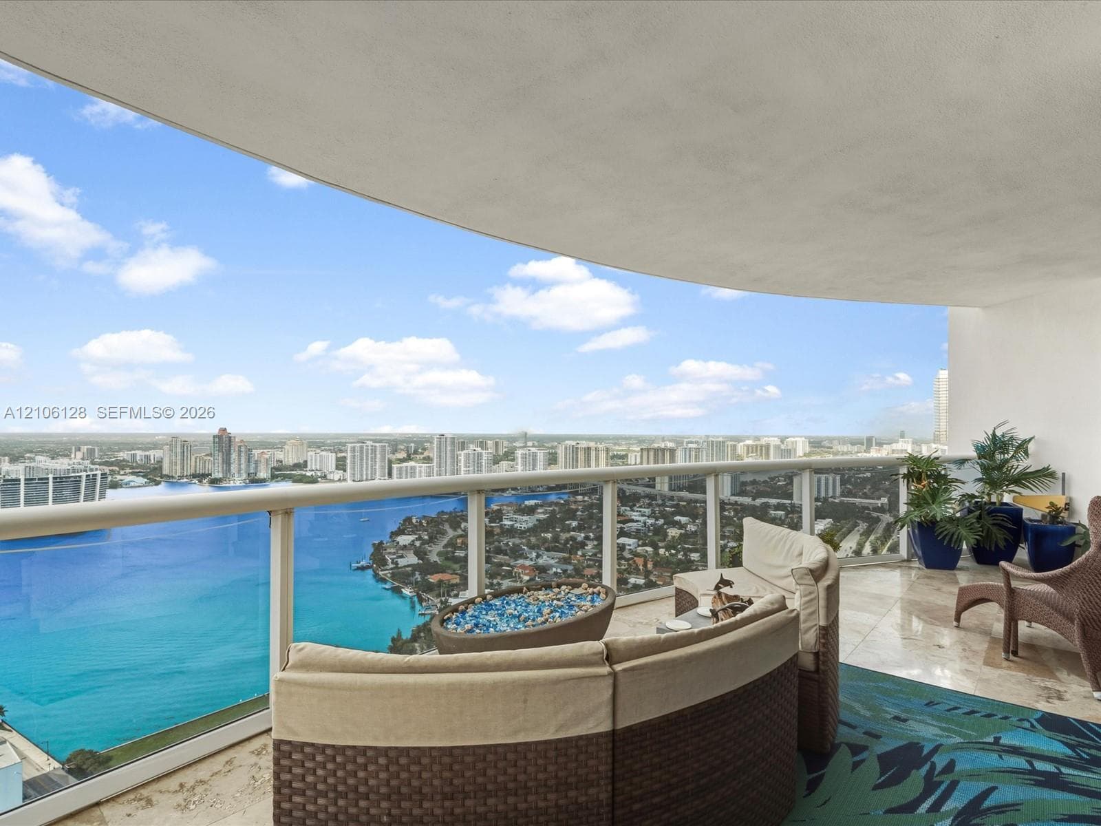Covered terrace featuring polished stone flooring and glass panel railing