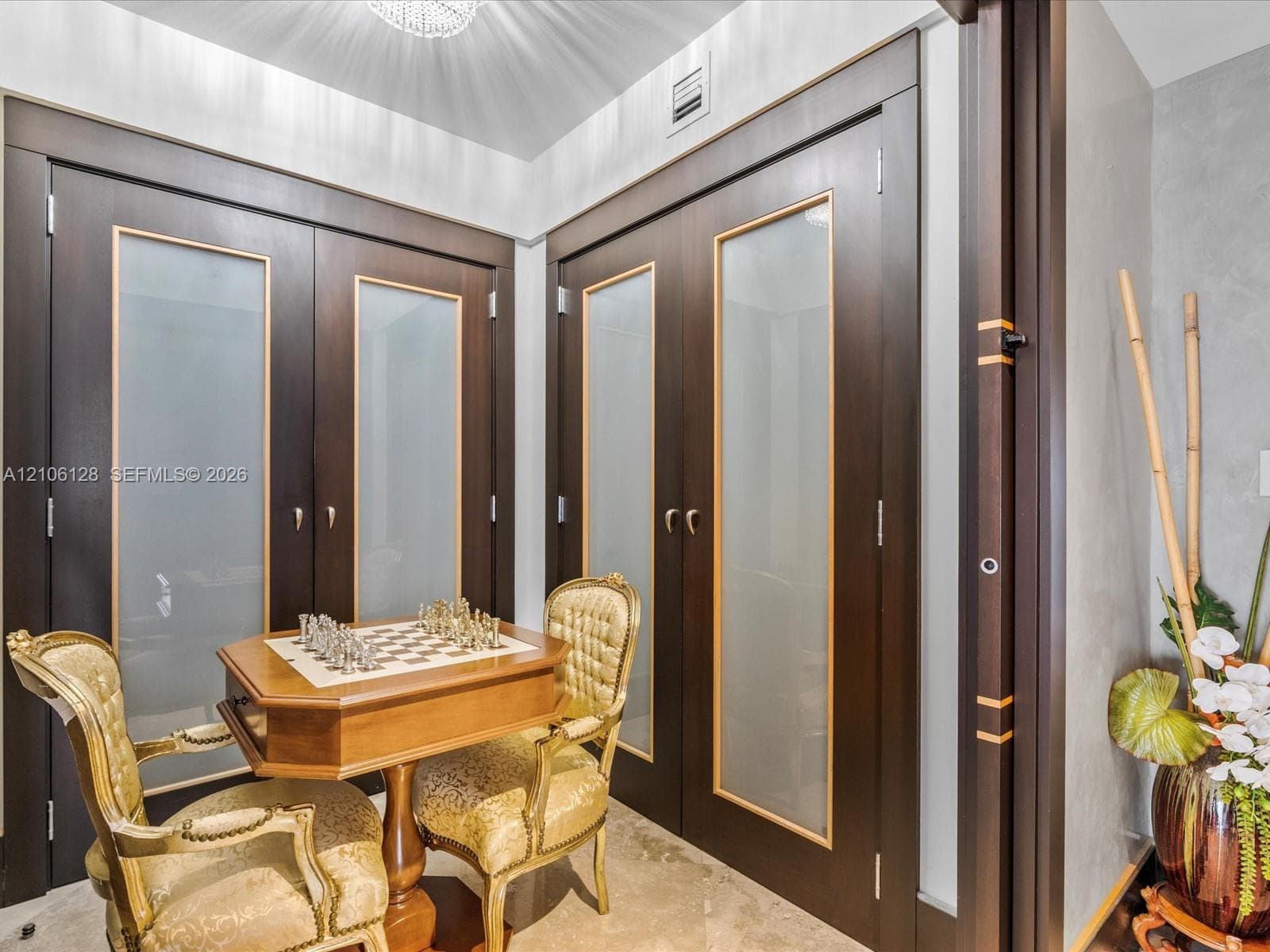 Double dark-wood doors featuring frosted glass panels with gold trim, polished stone flooring, and ceiling-mounted light fixture