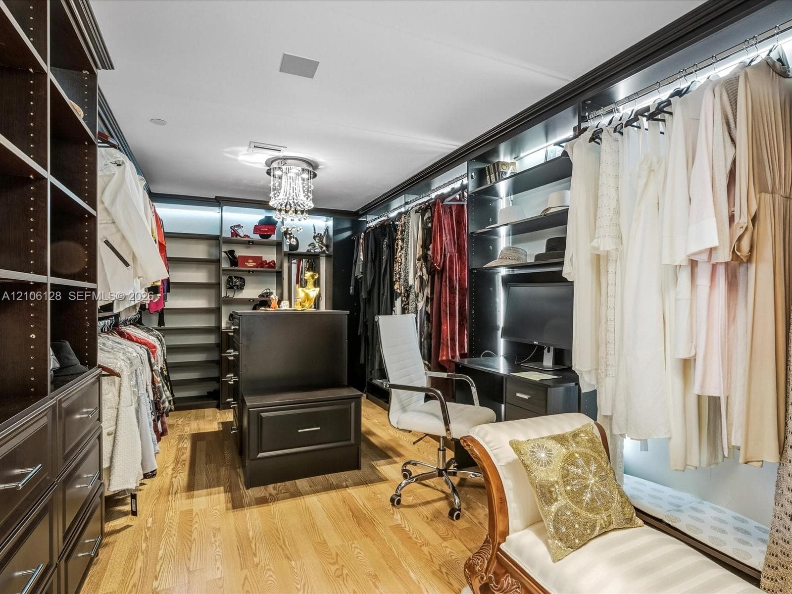 Custom dark wood-finish cabinetry, floor-to-ceiling built-in shelving, central island storage, integrated LED task lighting, and hardwood flooring