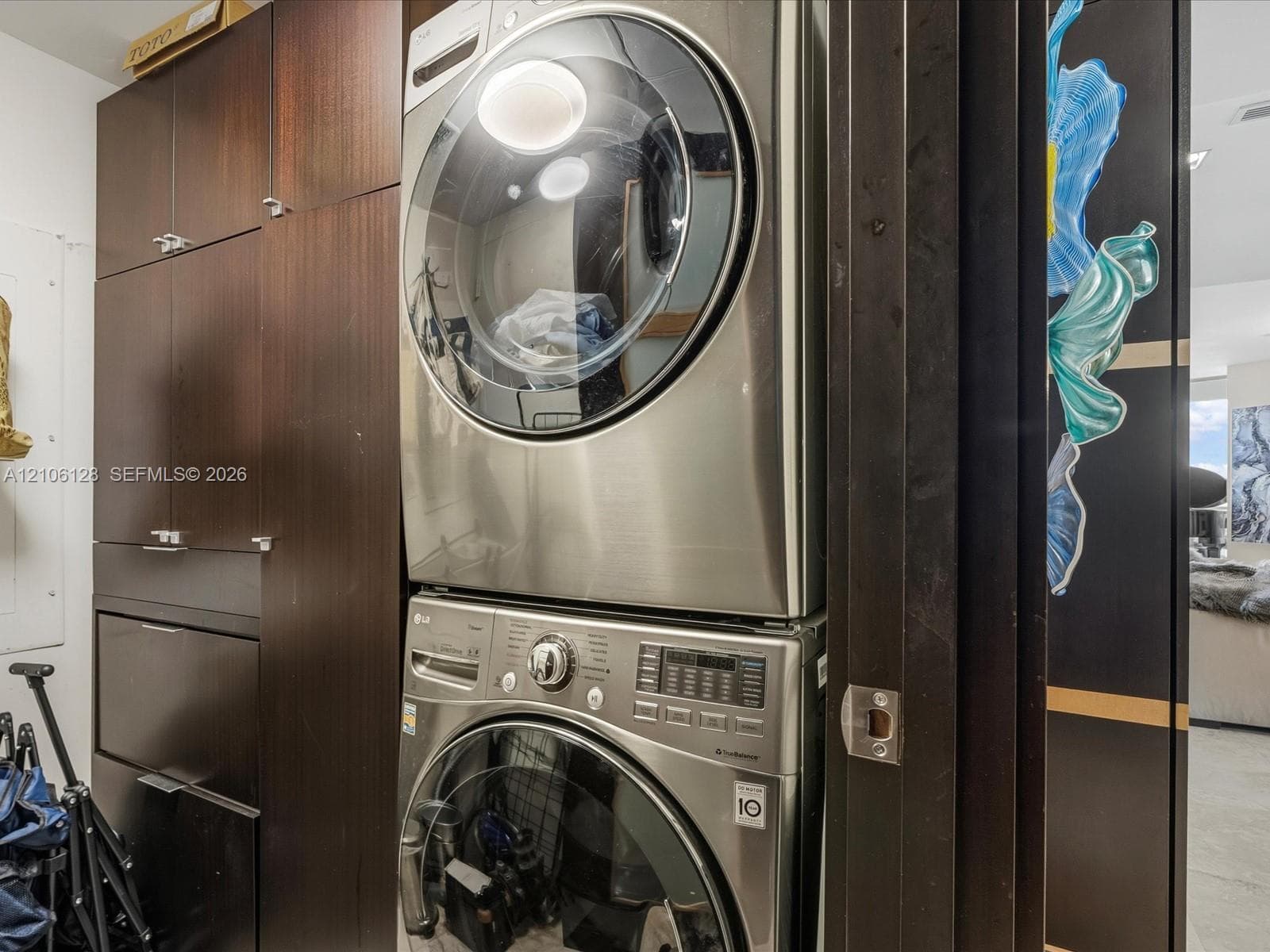 Stacked stainless steel laundry appliances paired with floor-to-ceiling dark wood-finish cabinetry