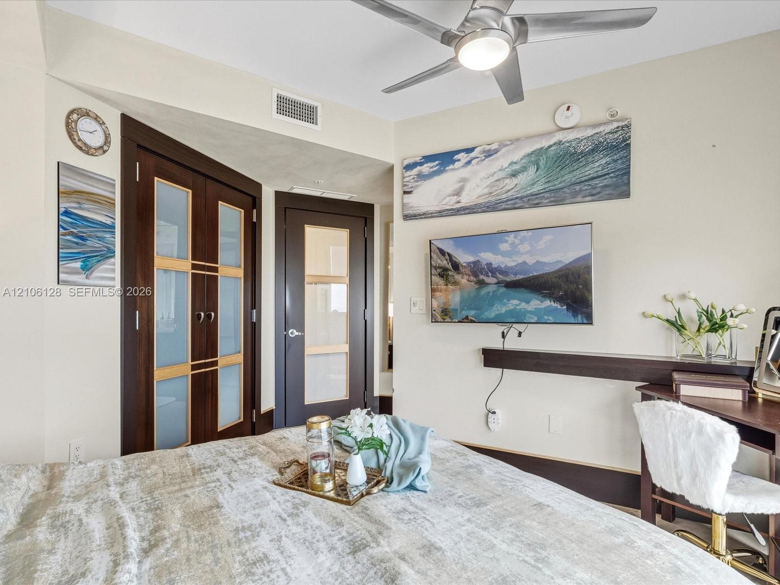 Custom dark-wood doors featuring frosted glass panels, brushed metal ceiling fan with integrated lighting, and horizontal wood accent shelf