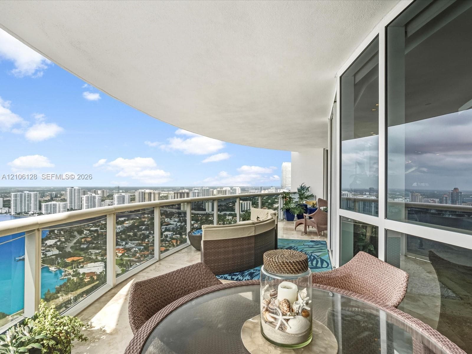 Covered wrap-around balcony featuring stone flooring, floor-to-ceiling glass paneling, and metal railing