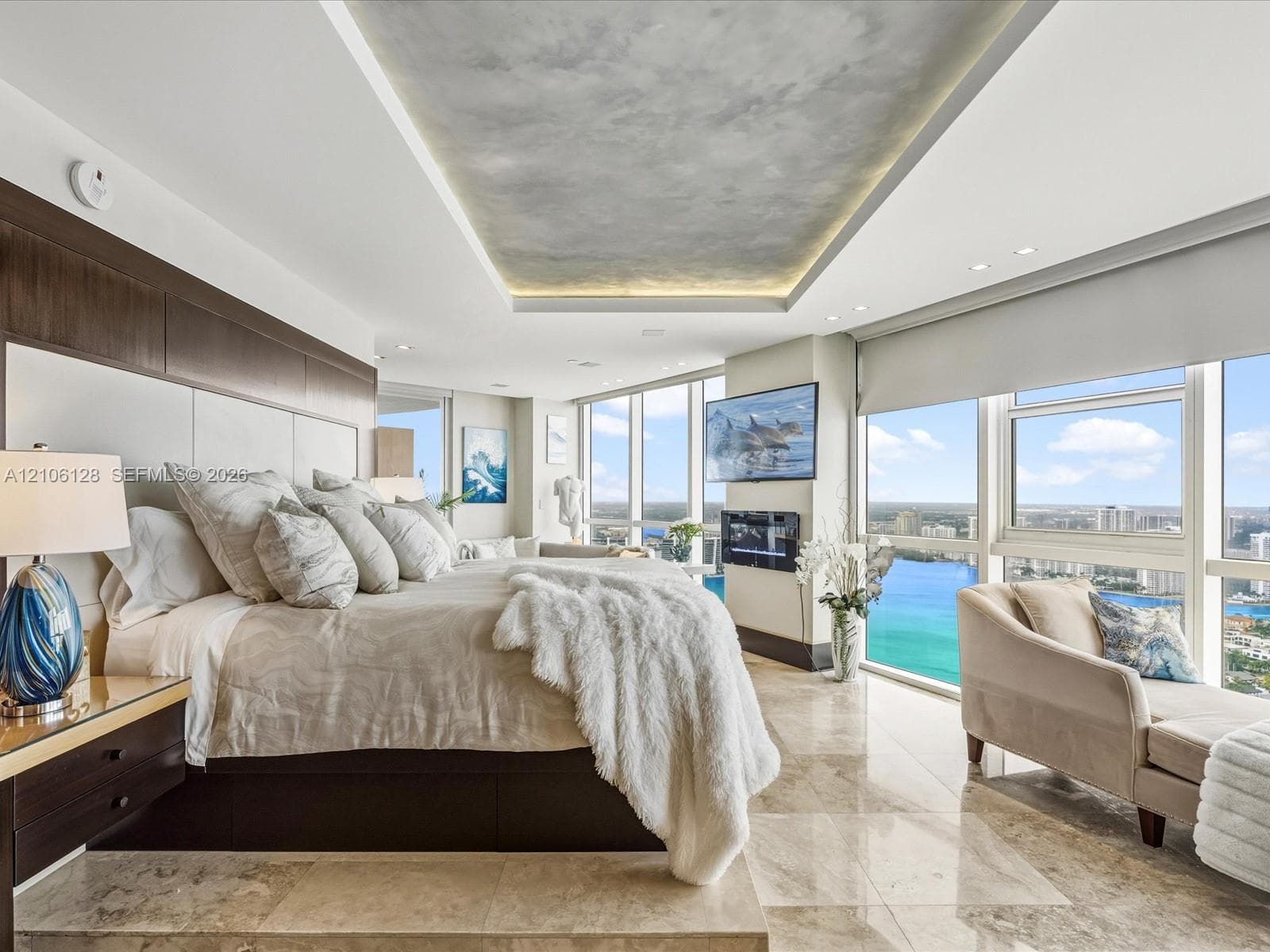 Floor-to-ceiling windows, stone tile flooring, built-in recessed ceiling lighting with textured inlay, and wall-mounted electric fireplace
