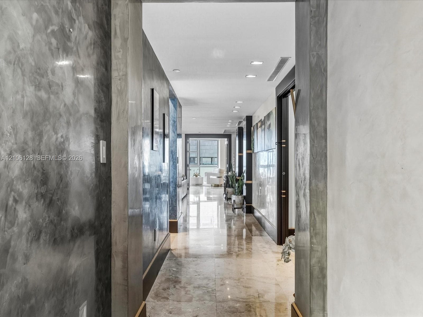 Hallway featuring polished stone flooring, custom Venetian plaster wall finishes, recessed ceiling lighting, and dark-finished door casing