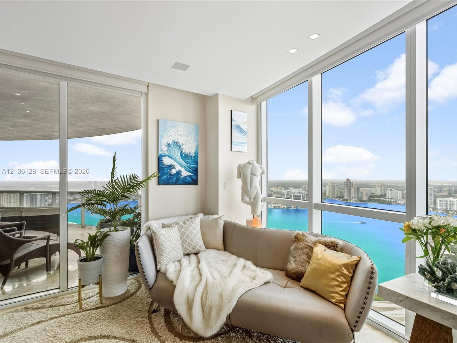 Floor-to-ceiling glass windows, expansive water backdrop, recessed ceiling lighting, sliding glass door, and wraparound balcony
