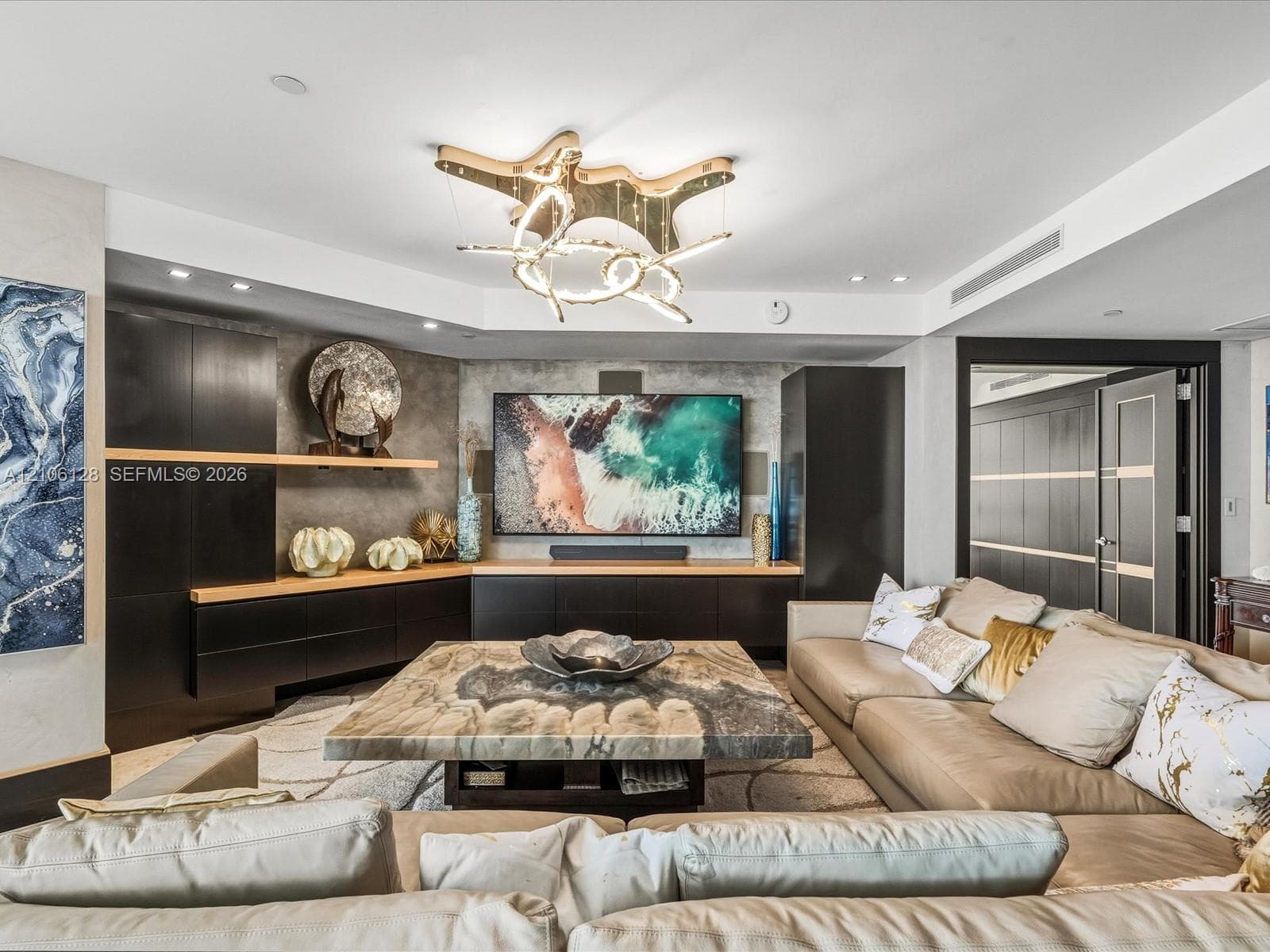 Custom built-in dark cabinetry with integrated shelving, stone-finish feature wall, and sculptural modern chandelier