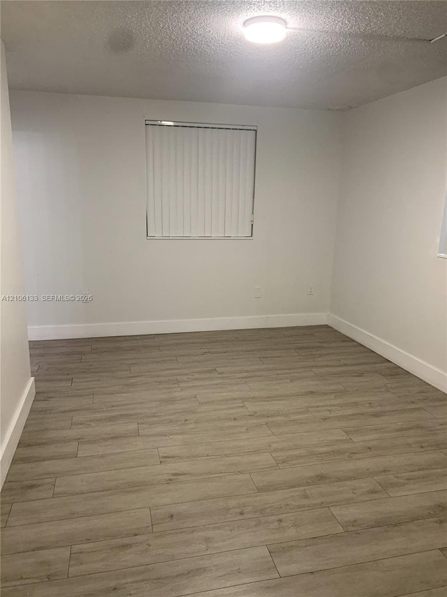 Neutral wall finishes, wood-finish flooring, and a flush-mount ceiling light fixture