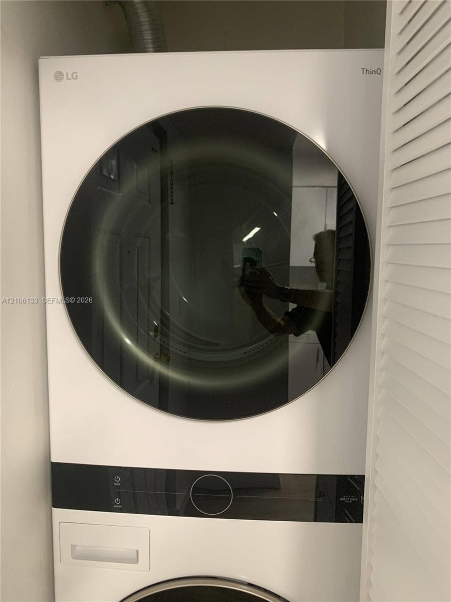 Stacked white front-loading laundry unit with integrated digital control panel and circular tempered glass door