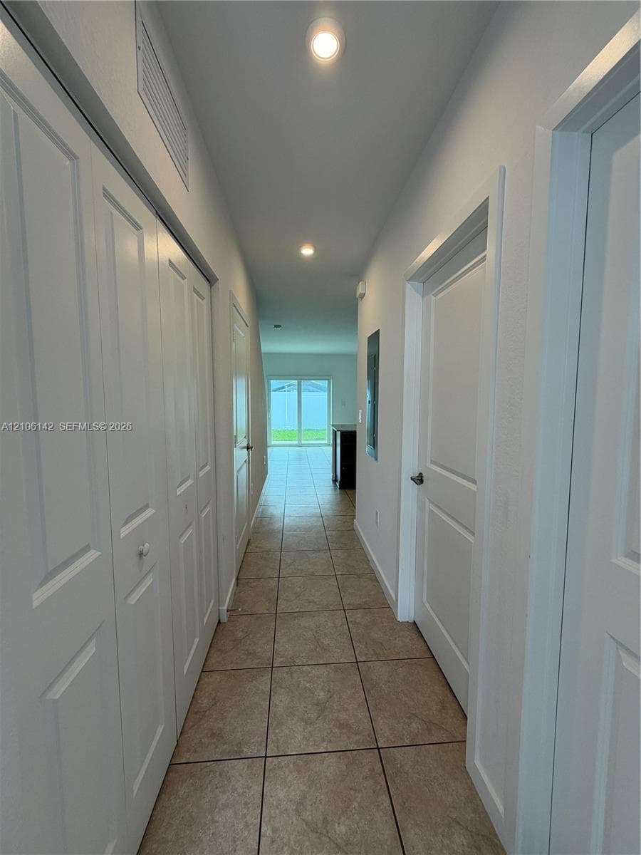 Hallway featuring neutral tile flooring, recessed lighting, and multiple interior doors with crisp white trim
