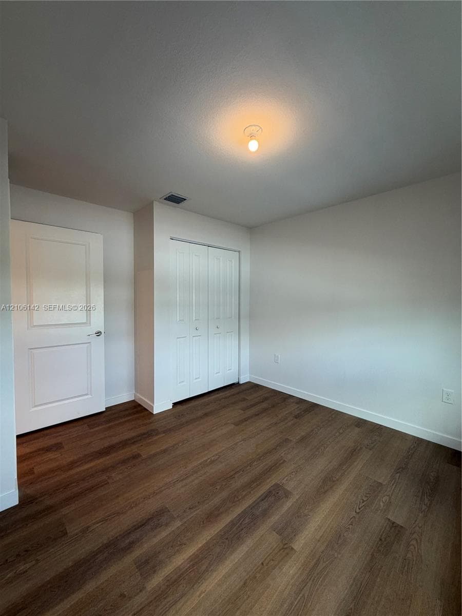 Interior space featuring wood-finish flooring, white panel doors, and a double-door closet