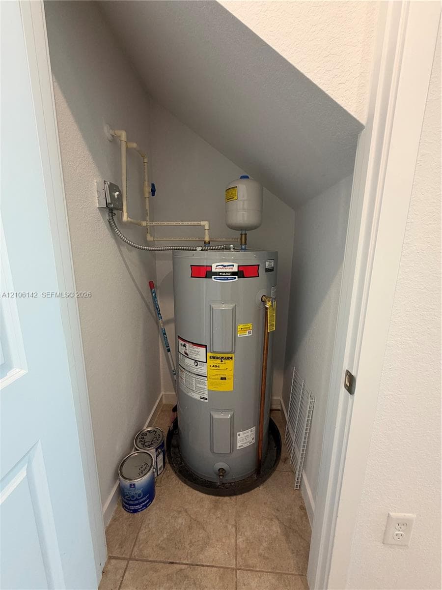 Utility closet featuring a water heater, expansion tank, and tiled flooring