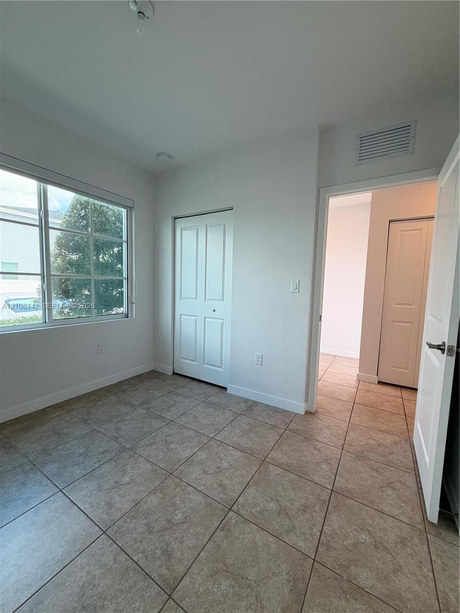 Neutral-toned ceramic tile flooring, multi-pane window, and interior paneled doors