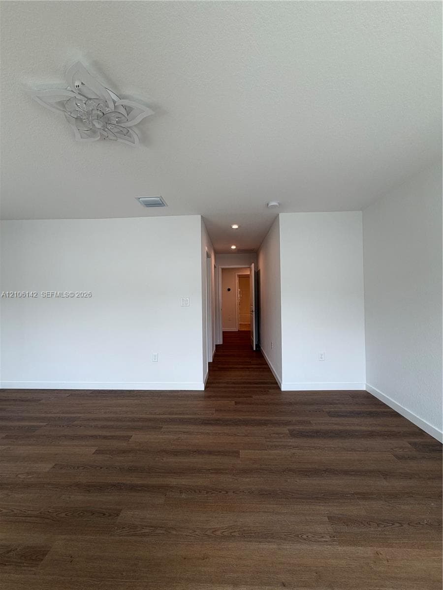 Interior space featuring wood-finish flooring, decorative ceiling-mounted light fixture, recessed lighting, and white walls