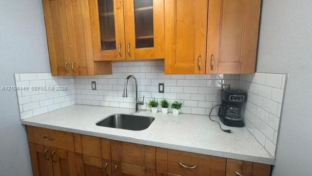 Natural wood cabinetry, white subway tile backsplash, solid-surface countertops, stainless steel undermount sink, and high-arch pull-down kitchen faucet