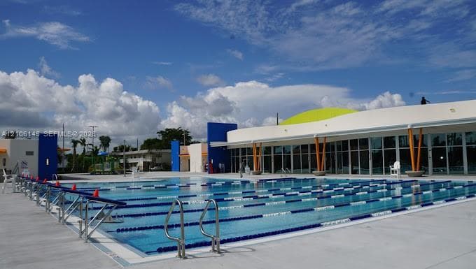 Multi-lane lap pool featuring metal handrails, integrated starting blocks, and expansive concrete decking