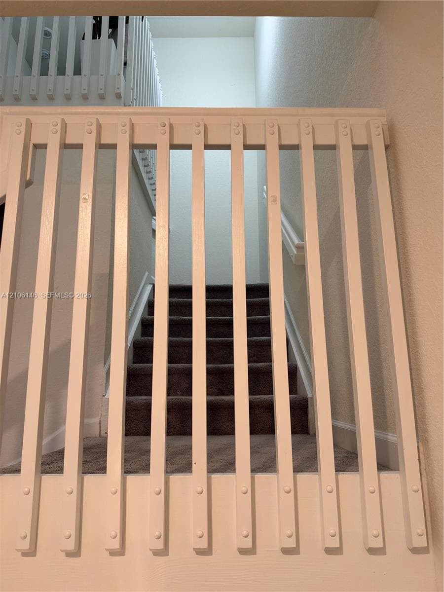 White wooden vertical baluster gate with recessed hardware and carpeted stairway