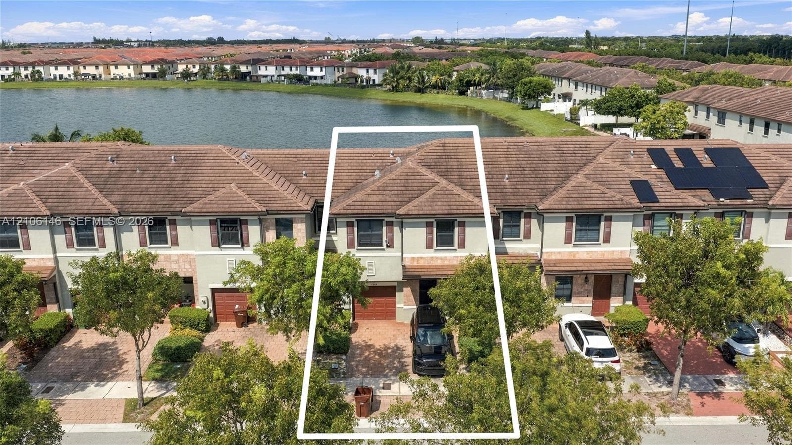 Waterfront townhouse exterior featuring a tiled roof, paver driveway, single-car garage, and stucco facade