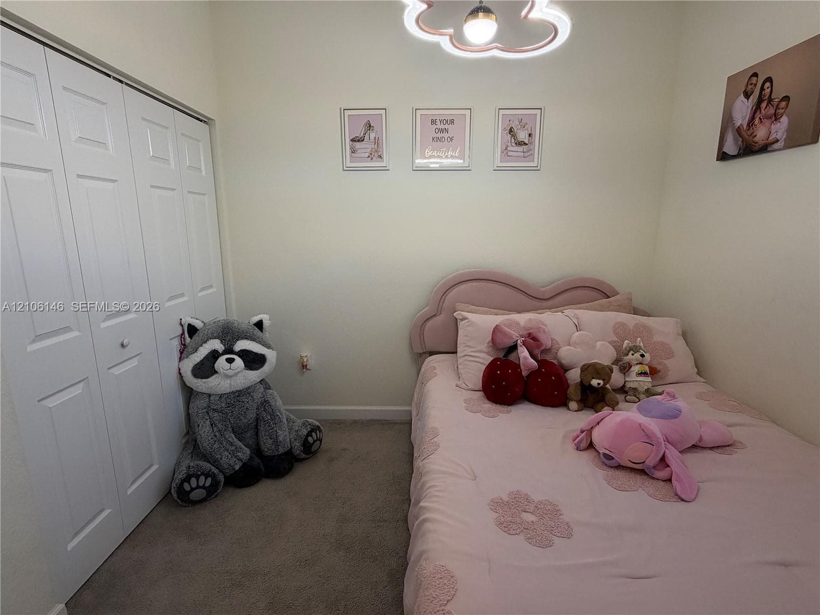 Room featuring carpeting, bi-fold closet doors, and a decorative cloud-shaped ceiling light fixture