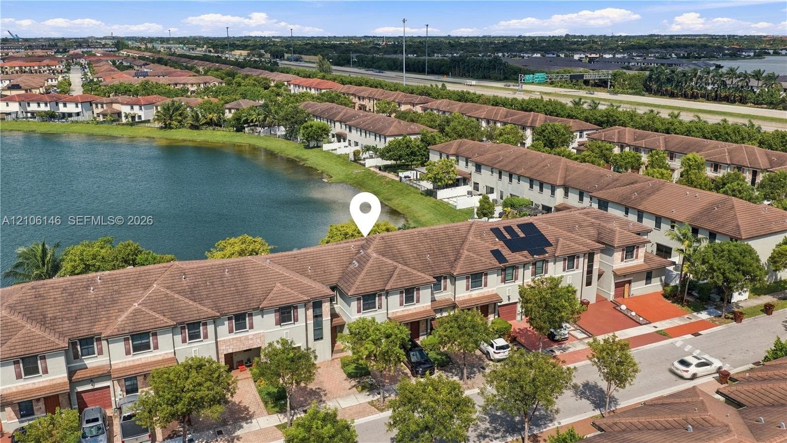 Multi-level townhome featuring a tiled roof, paver driveway, and waterfront positioning