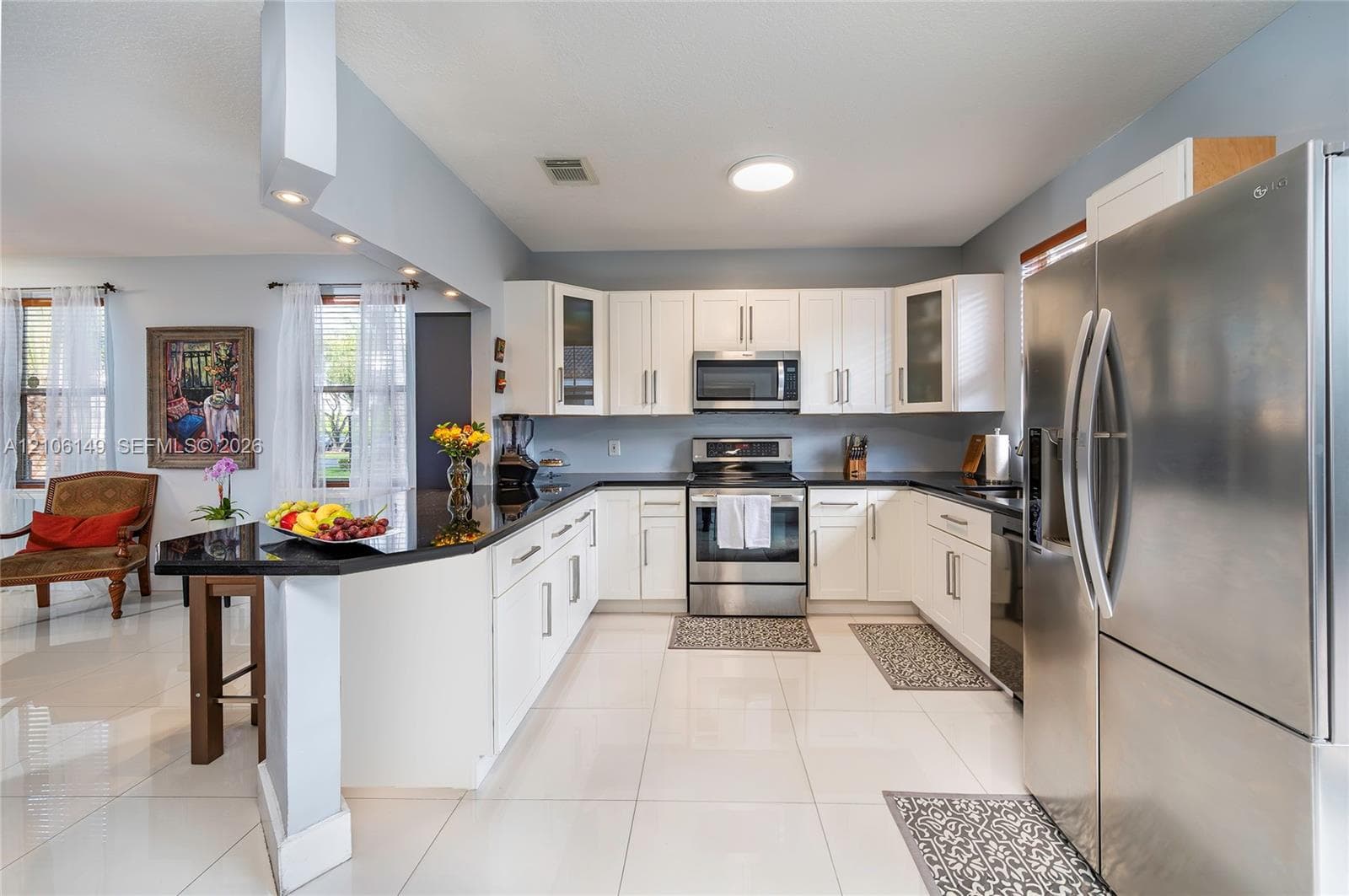 Kitchen featuring white shaker-style cabinetry, dark stone countertops, stainless steel appliances, and polished tile flooring