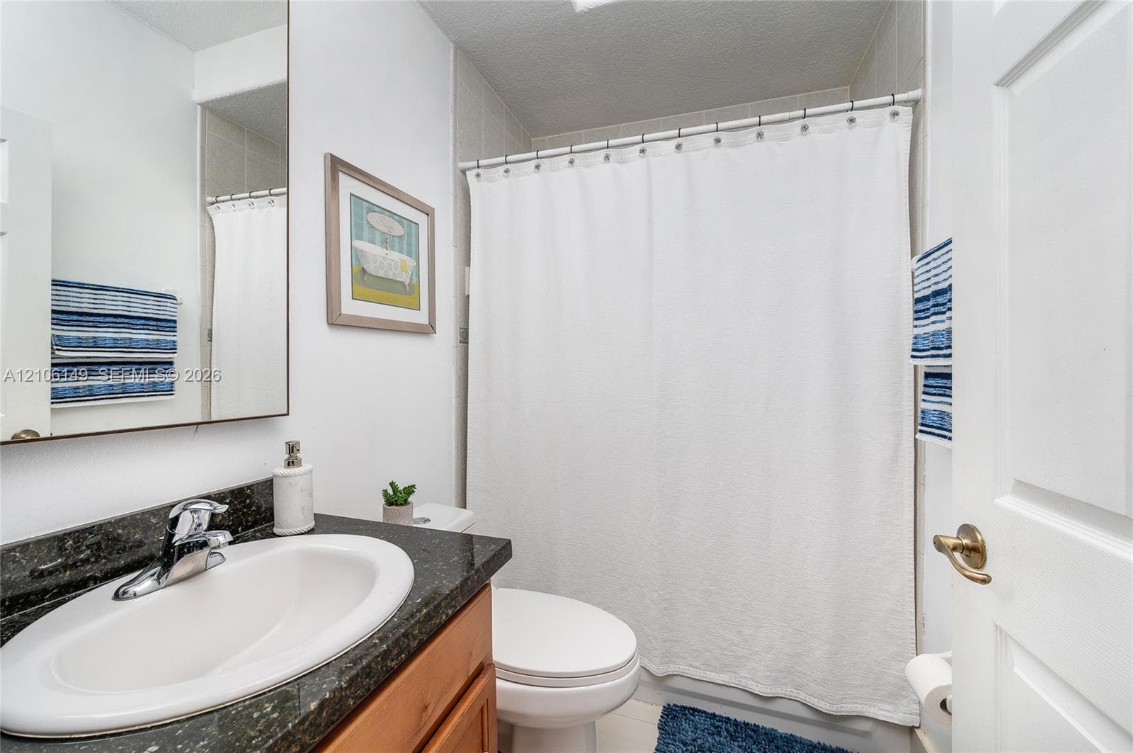 Bathroom featuring a vanity with a stone-finish countertop, integrated oval basin, and single-handle chrome faucet
