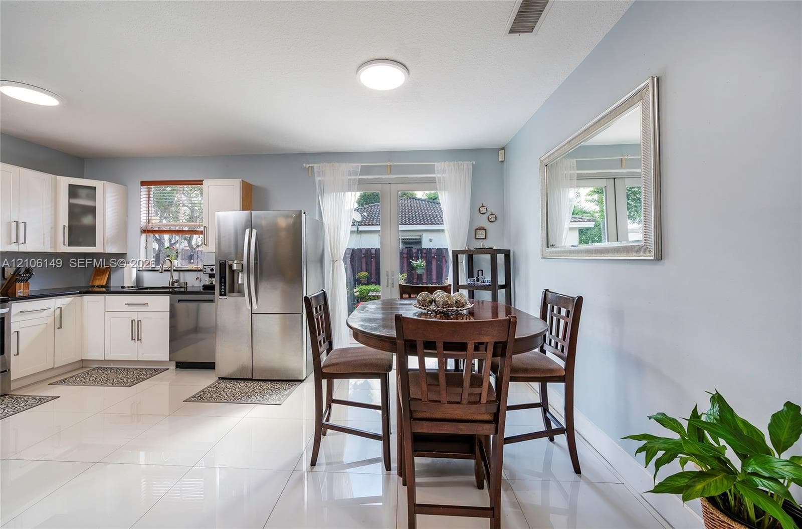 Kitchen featuring white cabinetry, stainless steel appliances, large-format tile flooring, and glass French doors
