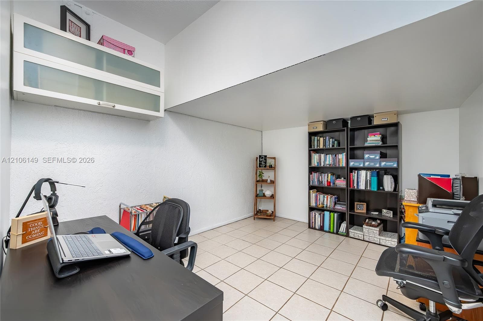 Room featuring neutral ceramic tile flooring and wall-mounted white cabinetry with frosted glass doors