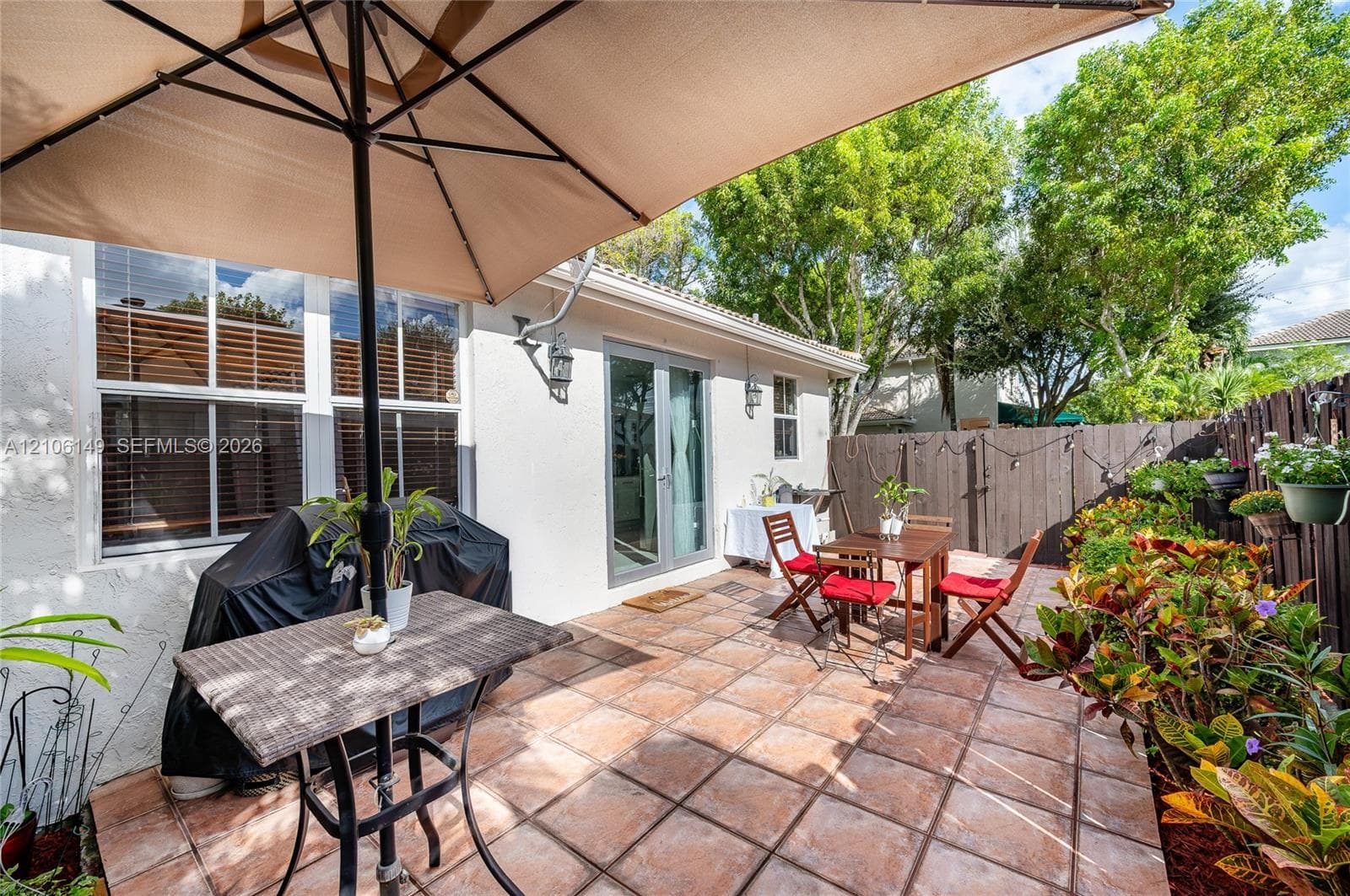Private patio featuring ceramic tile flooring, privacy fencing, and exterior wall-mounted lighting