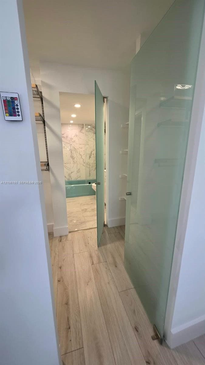 Frosted glass door, wood-finish flooring, and recessed ceiling lighting