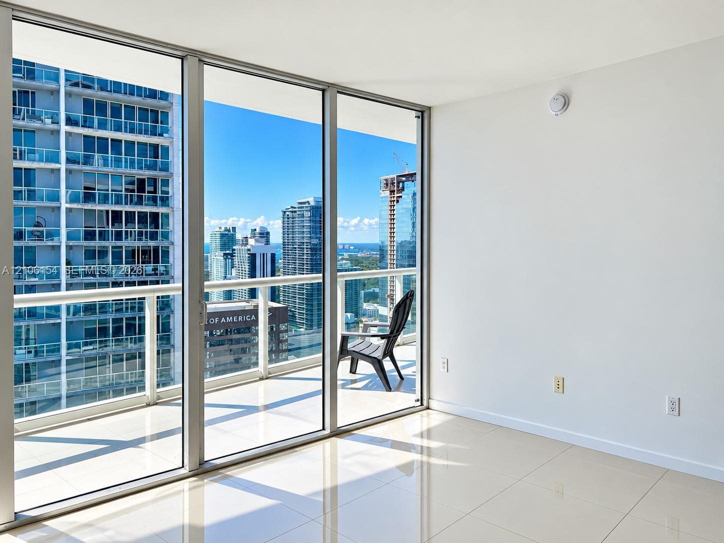 Floor-to-ceiling glass walls, wrap-around balcony with metal railing, and large-format porcelain tile flooring