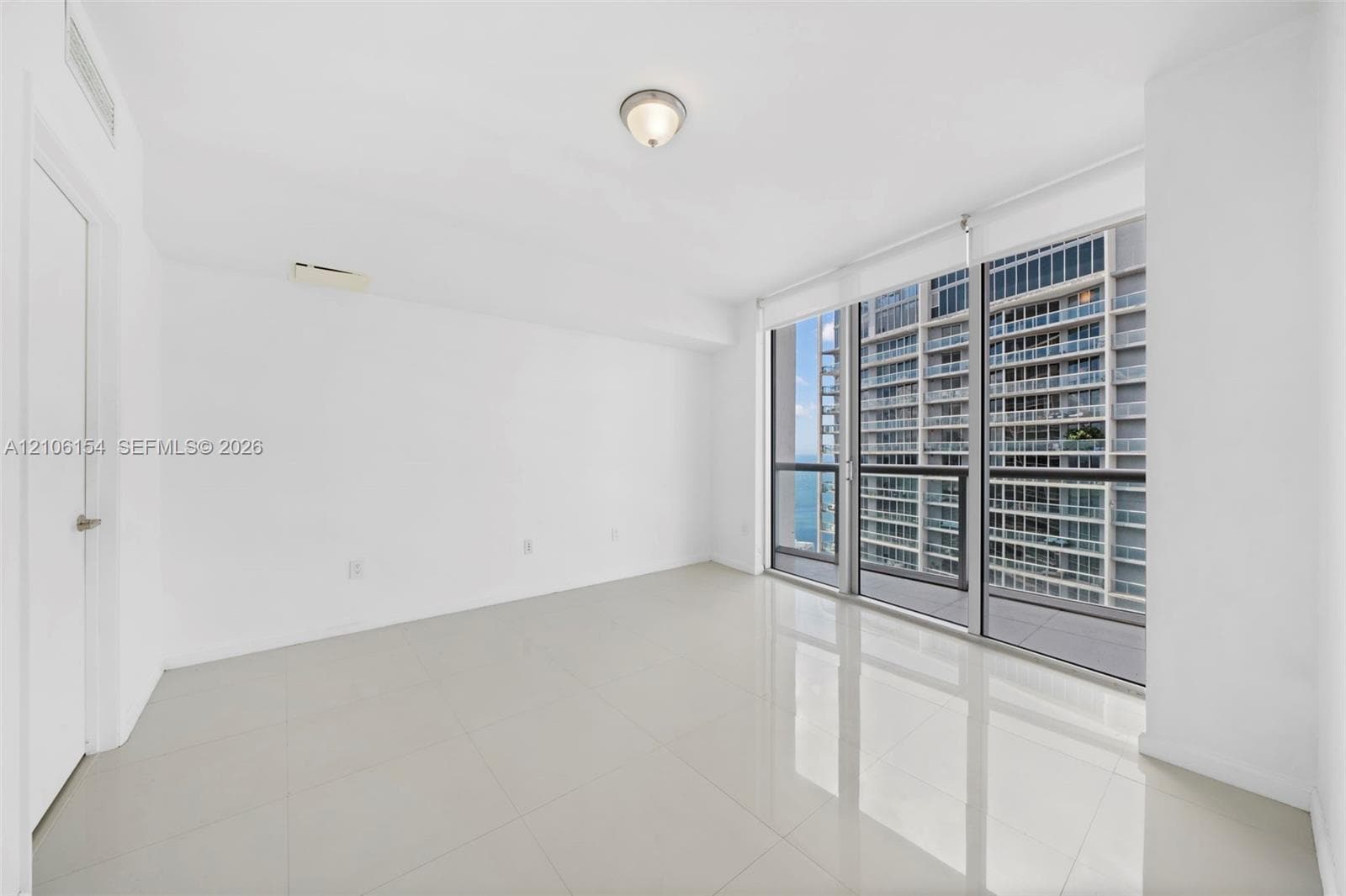 Floor-to-ceiling glass paneling, polished tile flooring, balcony access, and flush-mount ceiling lighting