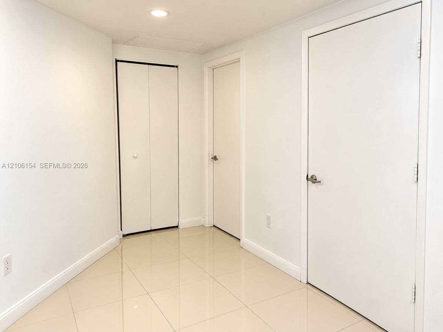 Neutral-toned ceramic tile flooring, clean white wall finishes, flush-panel doors, and recessed ceiling lighting
