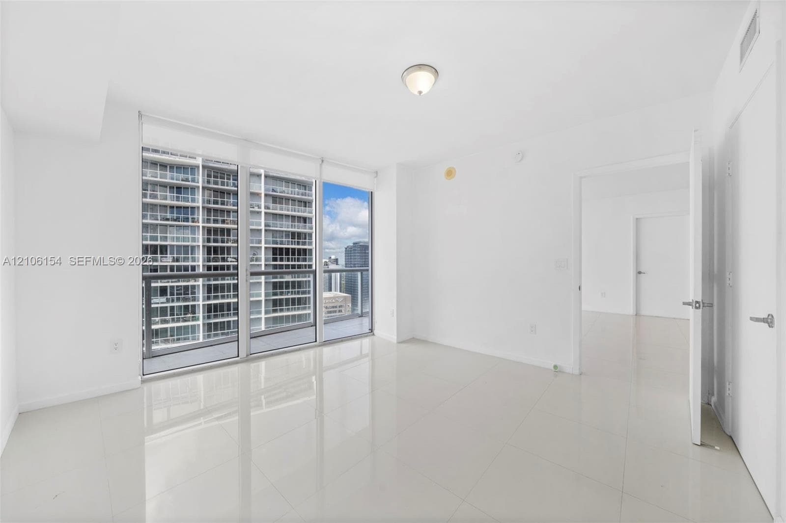 Floor-to-ceiling windows with balcony access, ceramic tile flooring, and neutral wall finishes