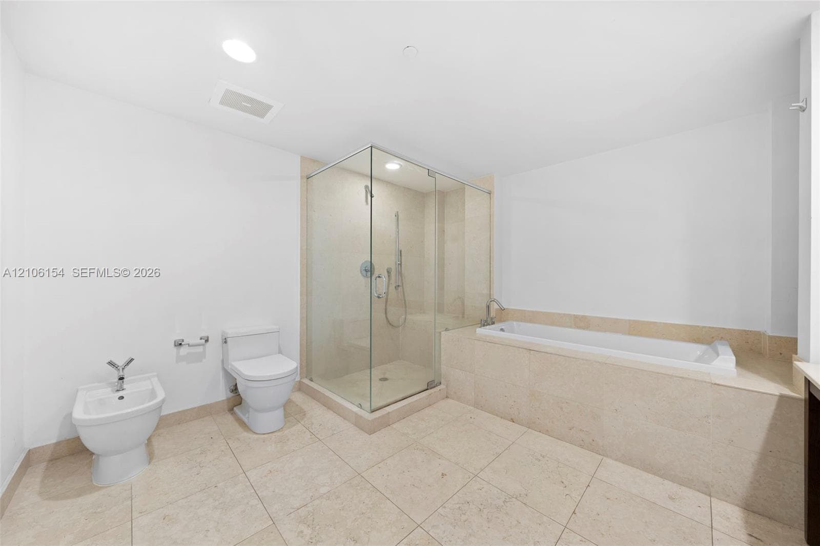 Bathroom featuring a glass-enclosed shower, deep-soaking bathtub, stone tile flooring, and integrated bidet