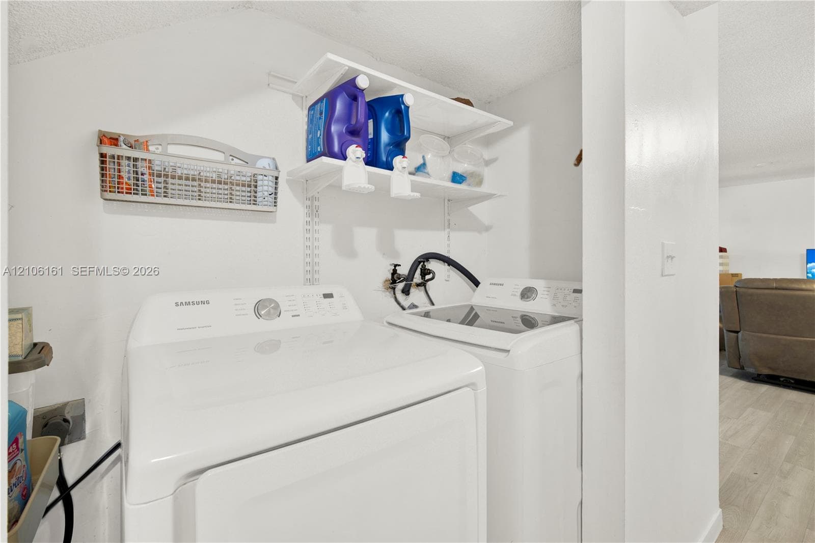 Laundry area featuring white top-loading washer and dryer with adjustable wall-mounted shelving