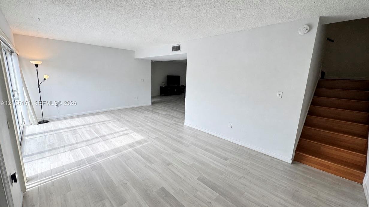 Open-concept floor plan featuring wood-finish flooring, staircase with wood treads, and sliding glass door