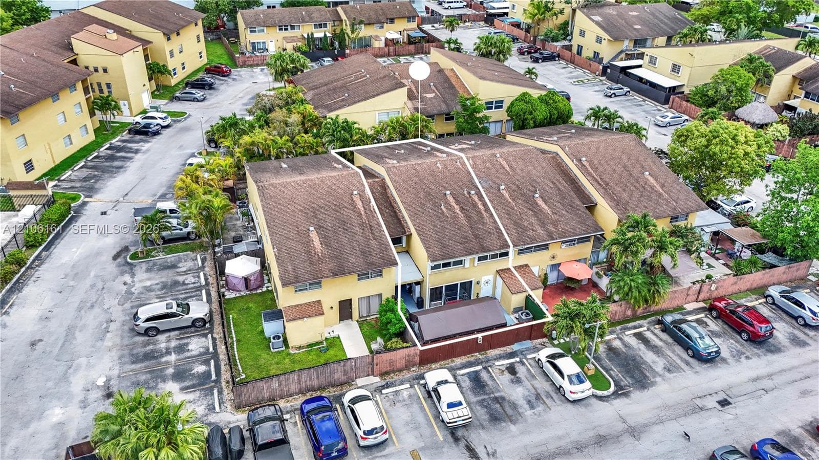 Two-story multi-family residence featuring a shingled roof, stucco exterior, fenced private patio area, and dedicated surface parking