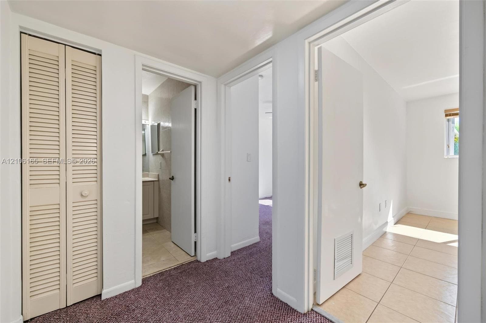 Louvered bi-fold closet doors, neutral wall finish, and low-pile carpeted flooring