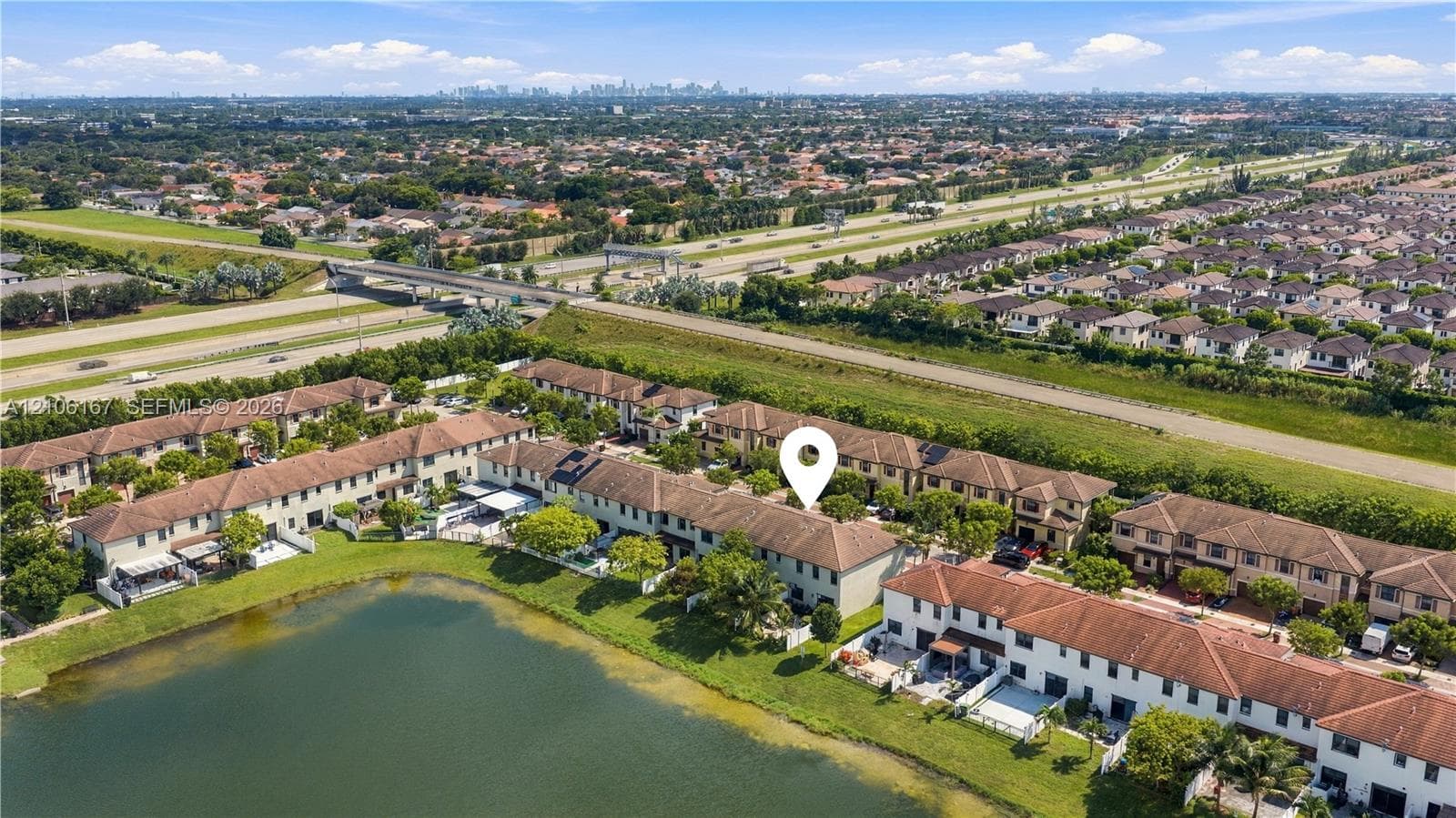 Aerial perspective of a multi-unit residential complex featuring tile roofing and waterfront positioning along a private pond