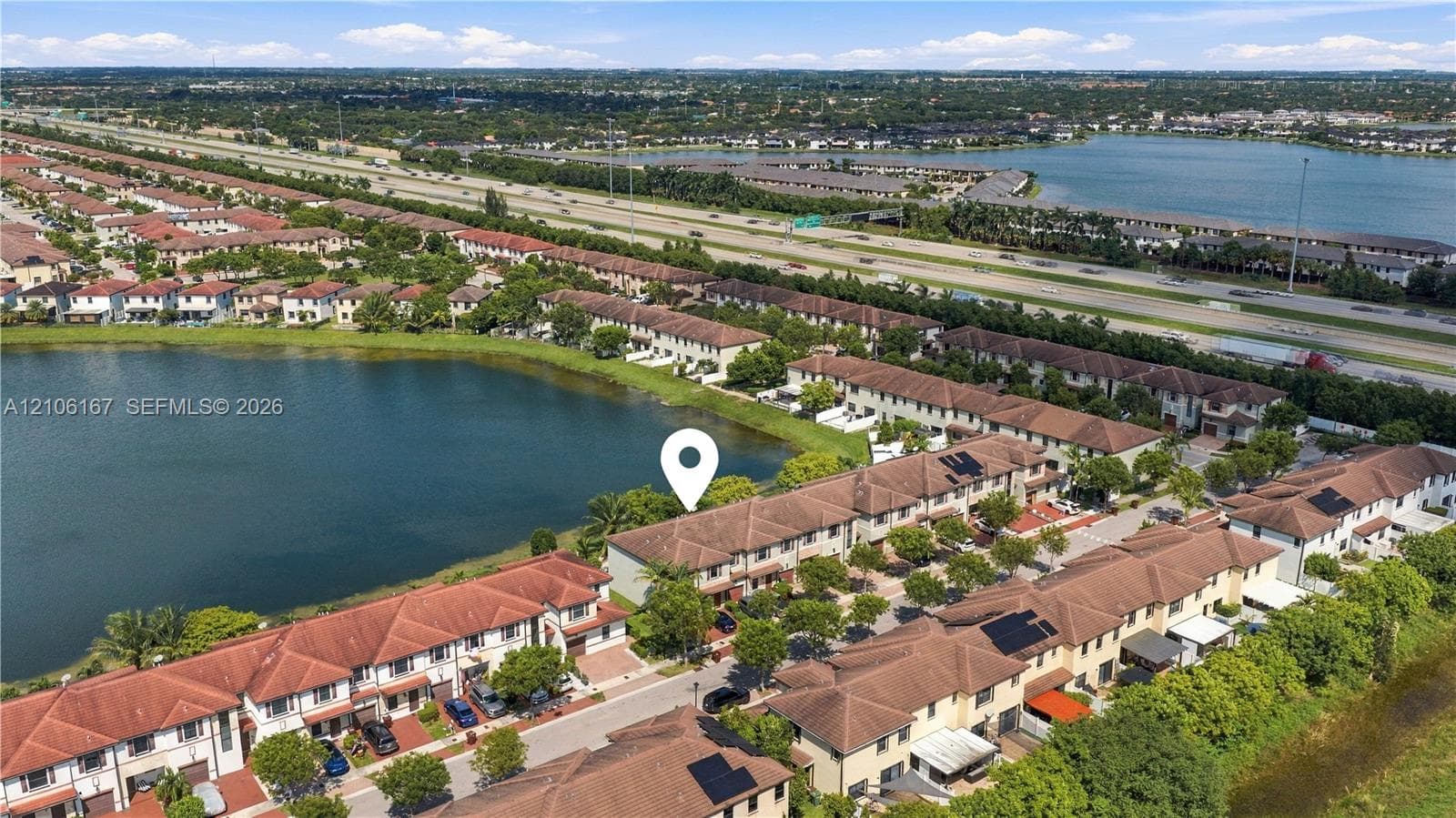 Aerial perspective of a multi-unit property featuring tile roofing and proximity to a waterfront