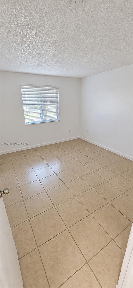 Neutral-toned tile flooring, white wall finish, and a window with installed horizontal blinds