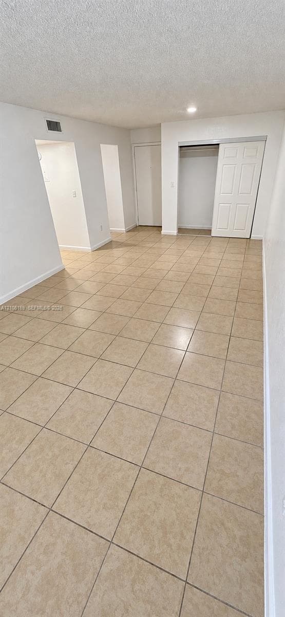 Neutral-toned ceramic tile flooring, recessed ceiling lighting, and a reach-in closet featuring a sliding paneled door
